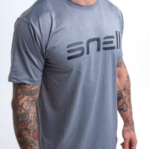 Portrait of a tattooed man posing in a gray 'snell' t-shirt in a studio with a white background.