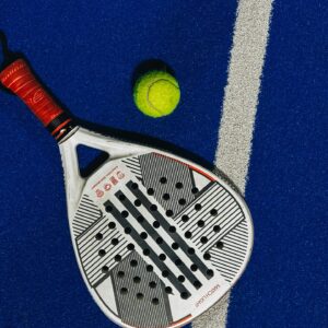 A padel racket and ball on a vibrant blue court background.